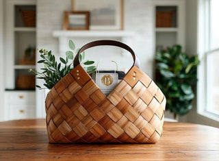 Luxury woven wooden gift basket with leather handle displayed on a wooden table in a bright home interior – elegant curated gift basket for corporate gifting, client appreciation, and professional relationships.