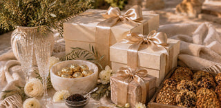 Luxury gift boxes with champagne satin ribbons, crystal flutes, gourmet chocolates and artisan treats styled in an elegant neutral setting for Biggest Little Baskets’ $1,000 & Up Collection