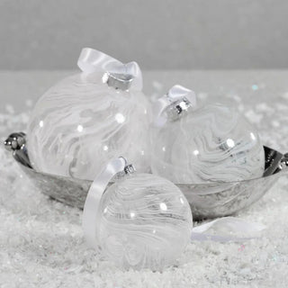 Set of white watercolor glass ball ornaments with satin ribbon in silver bowl on snowy surface  - hand crafted glass holiday decor for modern minimalistic styling