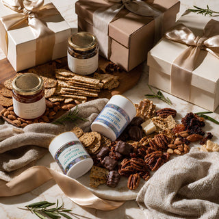 A Styled photo of Biggest Little Baskets $450 Gifting Tier custom curated gift box of artisan and gourmet food items including confiture jams, honey, nuts, and a keepsake item. 