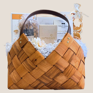 Woven brown Biggest Little Baskets' Classic Gourmet Charcuterie Gift basket filled with food and gift items on a neutral background