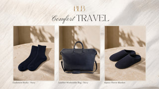 A promotional collage for Comfort Travel by BLB, featuring three navy blue travel-oriented items: a pair of cashmere socks, a leather weekend bag, and a pair of alpaca throw slippers, each shown in a styled interior setting on a beige stone surface with soft shadows.