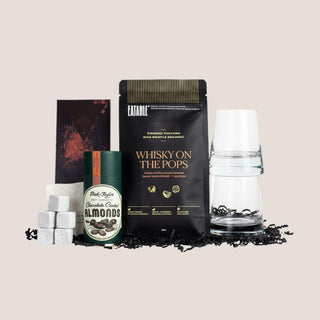 Complete Deluxe Sip & Savor whiskey gift assortment with tumblers, soapstone cubes, popcorn, chocolate bar, coated almonds, and truffles.