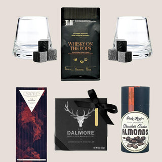 Deluxe Sip & Savor contents with two whiskey tumblers, soapstone cooling cubes, whisky-infused popcorn, dark chocolate, coated almonds, and truffles.