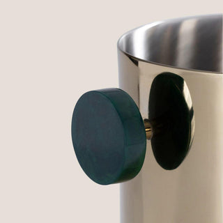 Close-up of one deep green resin handle attached to the reflective gold exterior of the stainless steel ice bucket.