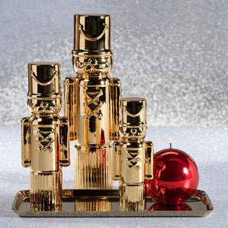 Gold ceramic soldier figurines with high gloss metallic finish displayed in three varying sizes on a festive coffee table -  modern sculptural holiday decor accent reflecting arm Light in elegant neutral living room setting.