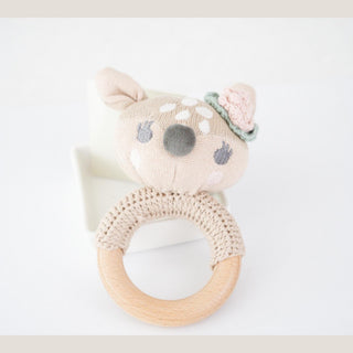 Crocheted fawn baby rattle with spotted pink-and-cream fawn head, mint flower detail, and natural wooden ring.