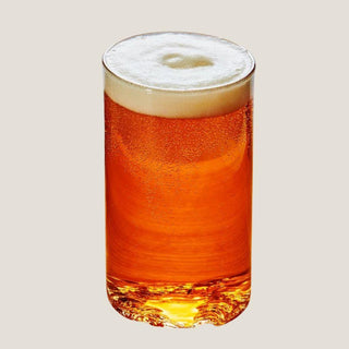 Single 16-ounce Lake Tahoe topographic pint glass filled with amber beer and a foam head against a warm neutral background.