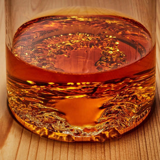 Close-up through an amber drink showing the detailed three-dimensional Lake Tahoe topographic relief inside the tumbler base.