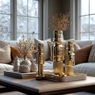 Set of gold ceramic soldiers in various sizes styled with books vases displayed on coffee table in elegant neutral living room with holiday decor - reflective high gloss nutcracker sculpture for sophisticated modern nutcracker holiday decor for luxury interiors 