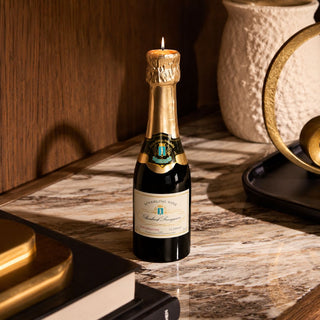 Mini unscented champagne bottle candle styled on a marble surface as a celebratory gift for hosts, congratulations, or milestones.