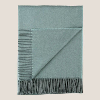 Folded Misty Mountain blue-green baby alpaca throw with a turned-back corner and coordinating fringe.