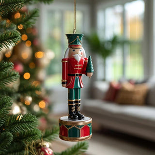 Festive rising nutcracker soldier ornament holding small Christmas tree in red and green with gold accents - elegant handcrafted holiday decoration.