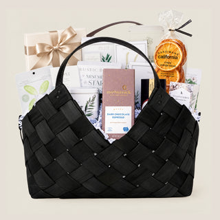 Front product view of the large black woven Office Harmony basket filled with seasonal chocolates, crackers, cookies, tea, nuts, fruit, and savory pantry foods.