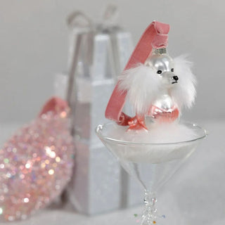 Parisian pup glass ornament with pink and white details resting on a silver pedestal  — elegant holiday décor featuring faux fur accents and reflective metallic ornaments