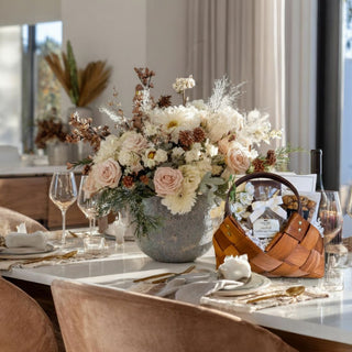 Petite Treat Gift Basket displayed on elegant dining table beside soft floral arrangement and gold cutlery.