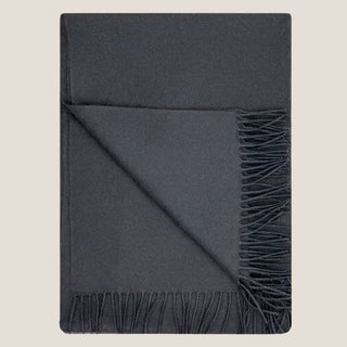 Folded Stargazer charcoal baby alpaca throw with a turned-back corner and matching dark fringe.