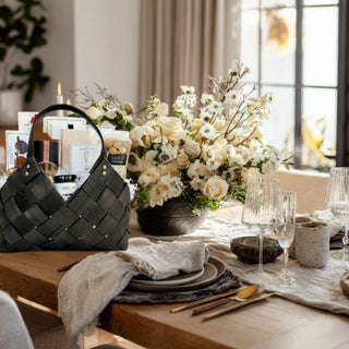 The Marlowe Gift Basket displayed on a wooden sideboard with candles and winter greenery for refined seasonal gifting.