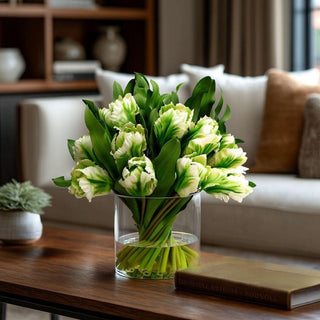 Two-tone green tulip faux floral arrangement styled on a warm wood coffee table with neutral furnishings, featuring realistic faux water and an elevated spring décor look inspired by high-end interiors.
