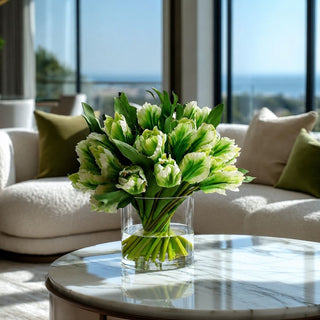 Two-tone green premade tulip faux floral arrangement styled on a marble coffee table with neutral furnishings, featuring realistic faux water and an elevated décor look inspired by high-end interiors.