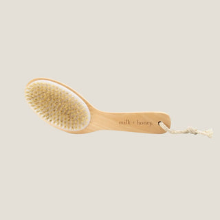 Wooden brush with natural bristles on a beige background, branded 'milk + honey'.