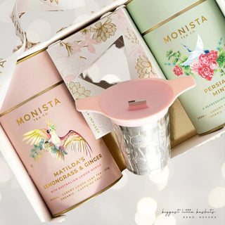 Close-up of Lemongrass & Ginger and Persian Mint tea canisters with a pink-handled metal stick infuser in an illustrated gift box.