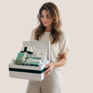 Woman holding the white Minted Moments holiday gift box against a neutral background.