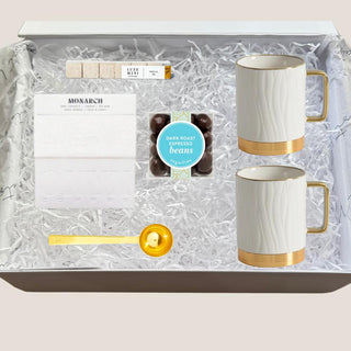 Open Petite Java Joy white gift box with two porcelain mugs, Monarch coffee, espresso beans, vanilla cubes, and gold scoop.
