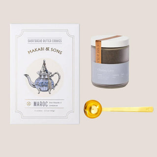 Flat lay of Charles Grey loose-leaf tea, rose pistachio cardamom shortbread, and a brushed gold tea scoop.