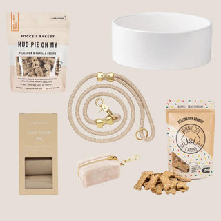 Flat lay of the flax Puppy Love collection with rope leash, ceramic bowl, canvas dispenser, waste bags, and two dog treats.