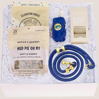 Open white Puppy Love gift box with marine-blue leash, matching waste-bag dispenser, refills and dog treats in white fill.