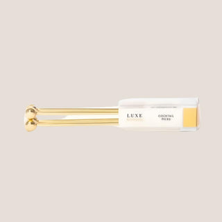 Set of four reusable gold cocktail picks with decorative round ends in a clear presentation box.