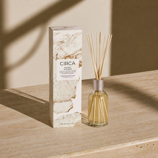 Sea Salt and Vanilla fragrance diffuser styled on a travertine surface with warm natural light, shown as one scent choice for the Welcome Home New Home Gift Box.