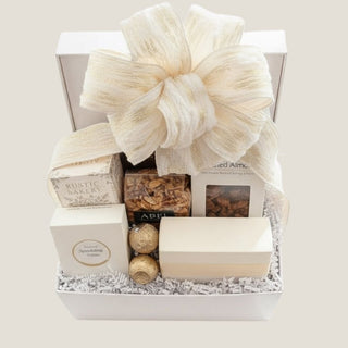 Overhead view of The Offering arranged in a white keepsake box and finished with an oversized cream ribbon woven with gold thread.