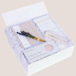 Angled view of the open Thinking of You gift box showing its soft neutral self-care pieces layered in white fill.