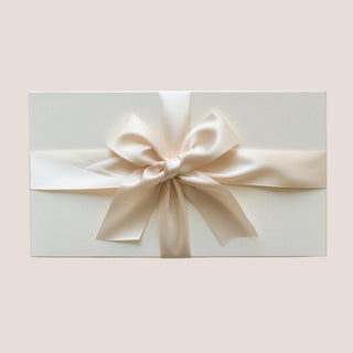 Closed matte white keepsake gift box tied with a wide ivory satin ribbon bow.