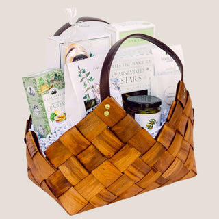 Angled product view of the medium brown Tried & True basket with curved handles, gold-tone rivets, and packaged foods.