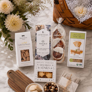 Flat lay of Tried & True contents including candied pecans, dark chocolate, dried orange slices, artisan crackers, and shortbread beside the brown basket.