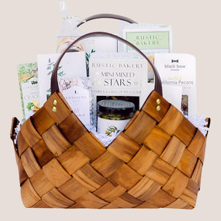 Front view of the brown woven Tried & True Gift Basket with white fill and a varied gourmet assortment.
