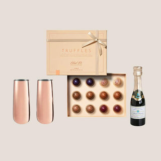 Two copper-plated stemless flutes, 12-piece truffle collection and miniature champagne bottle candle arranged together.