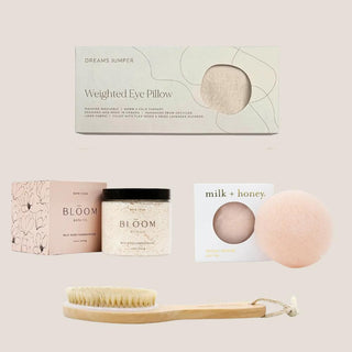 Wild rose bath soak, natural-bristle body brush, pink clay konjac sponge and lavender weighted eye pillow arranged together.