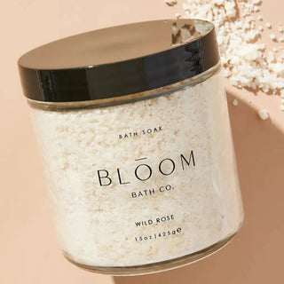 Bloom Bath Co. Wild Rose mineral bath soak in a clear jar with rose-toned salt crystals.