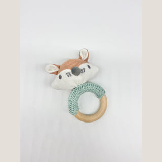 Crocheted fox baby rattle with rust-and-cream fox head, muted green handle, and natural wooden ring.