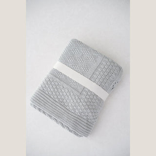 Folded gray cotton knit baby blanket secured with a white band, included in the Heirloom Baby Boy gift box.