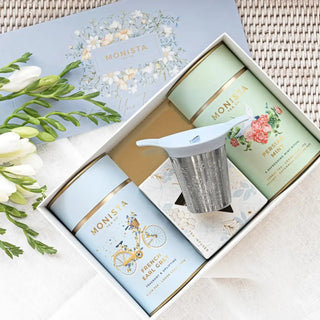 French Earl Grey and Persian Mint loose-leaf tea canisters with a metal stick infuser arranged in a blue floral presentation box.